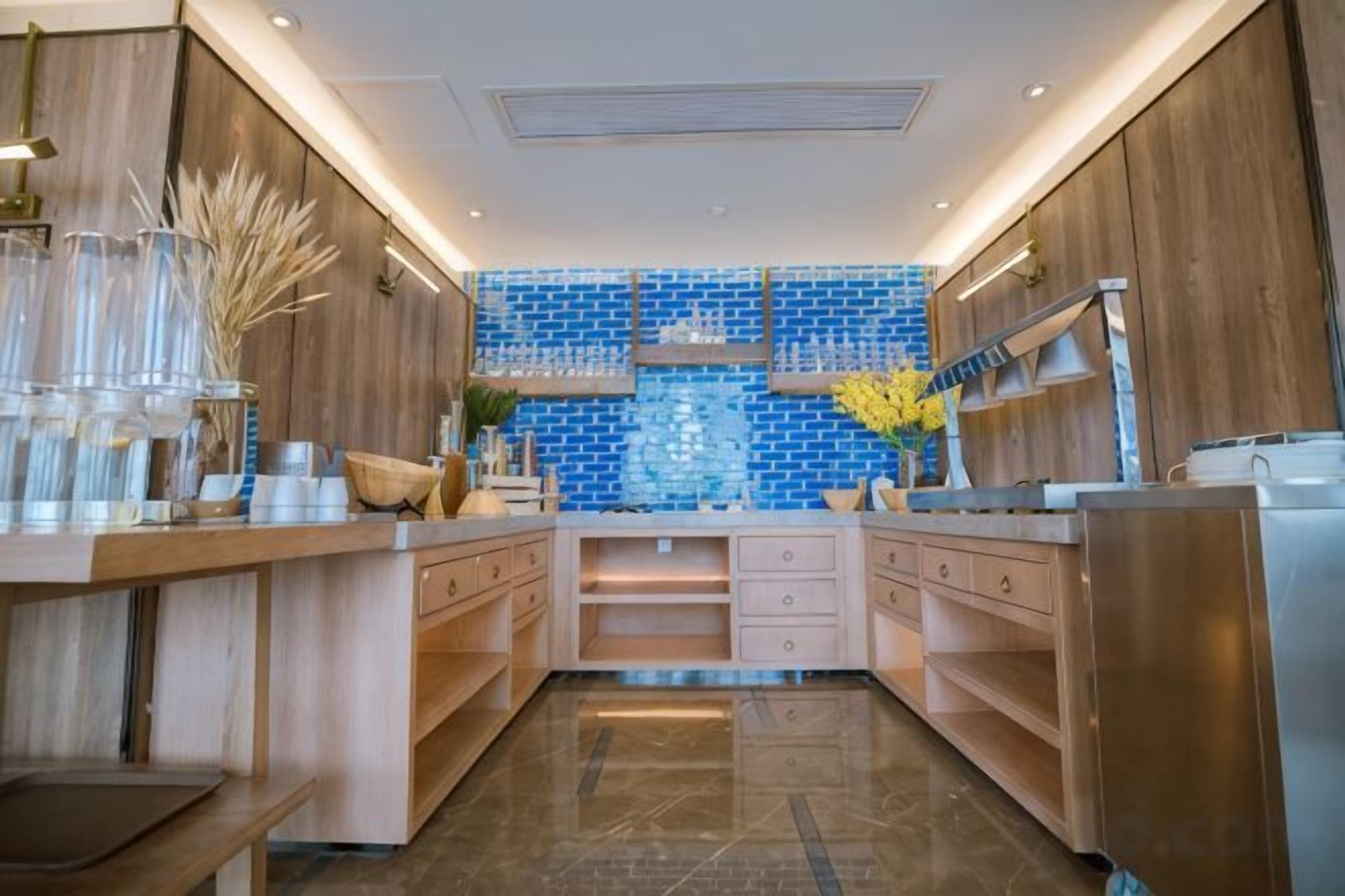 Una cocina moderna con armarios de madera, salpicadero de azulejos azules y electrodomésticos de acero inoxidable.