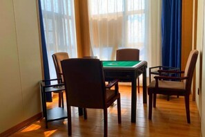 A room with a pool table, four chairs, and a window with curtains.