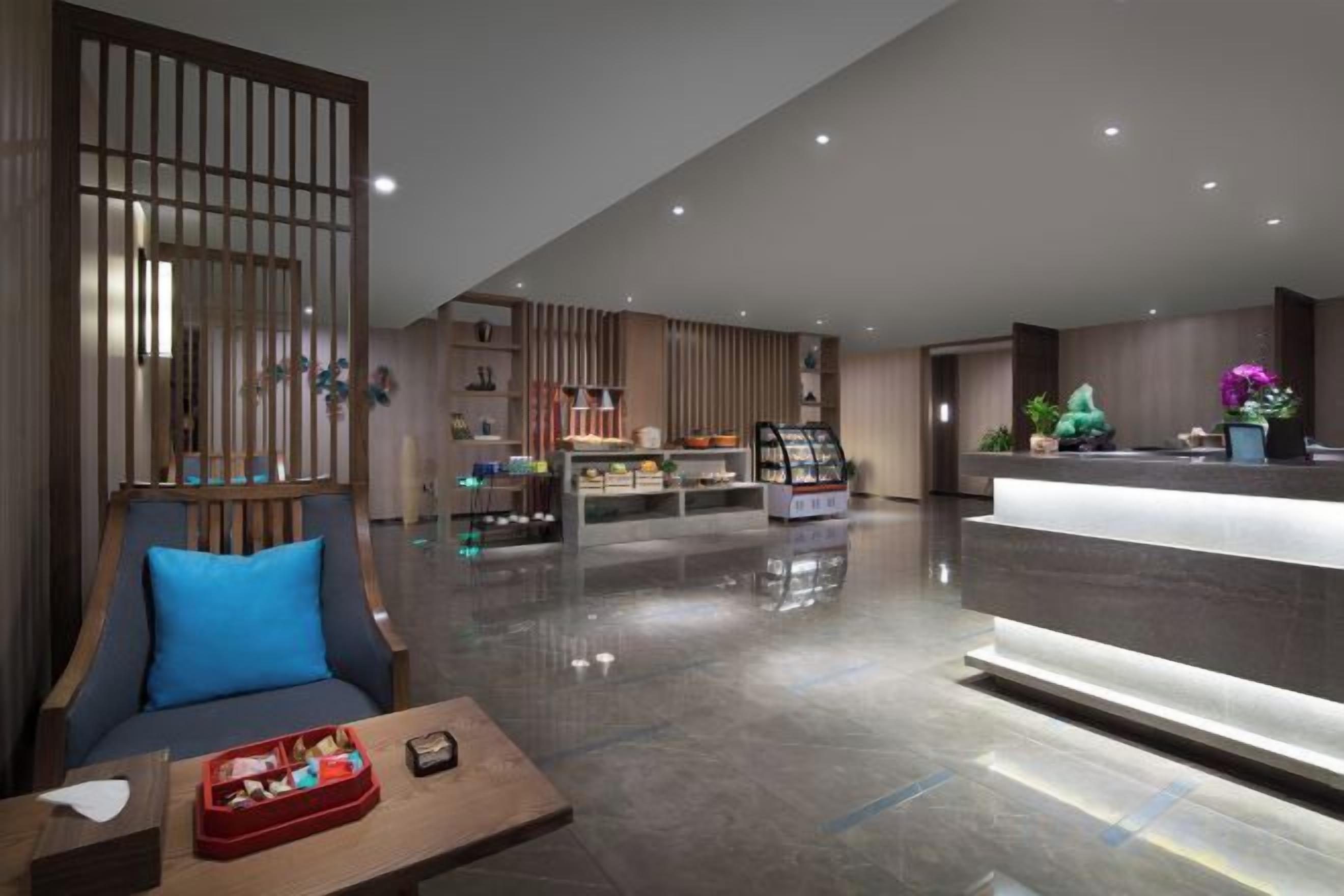 A modern hotel lobby with a reception desk, seating area, and a display case.