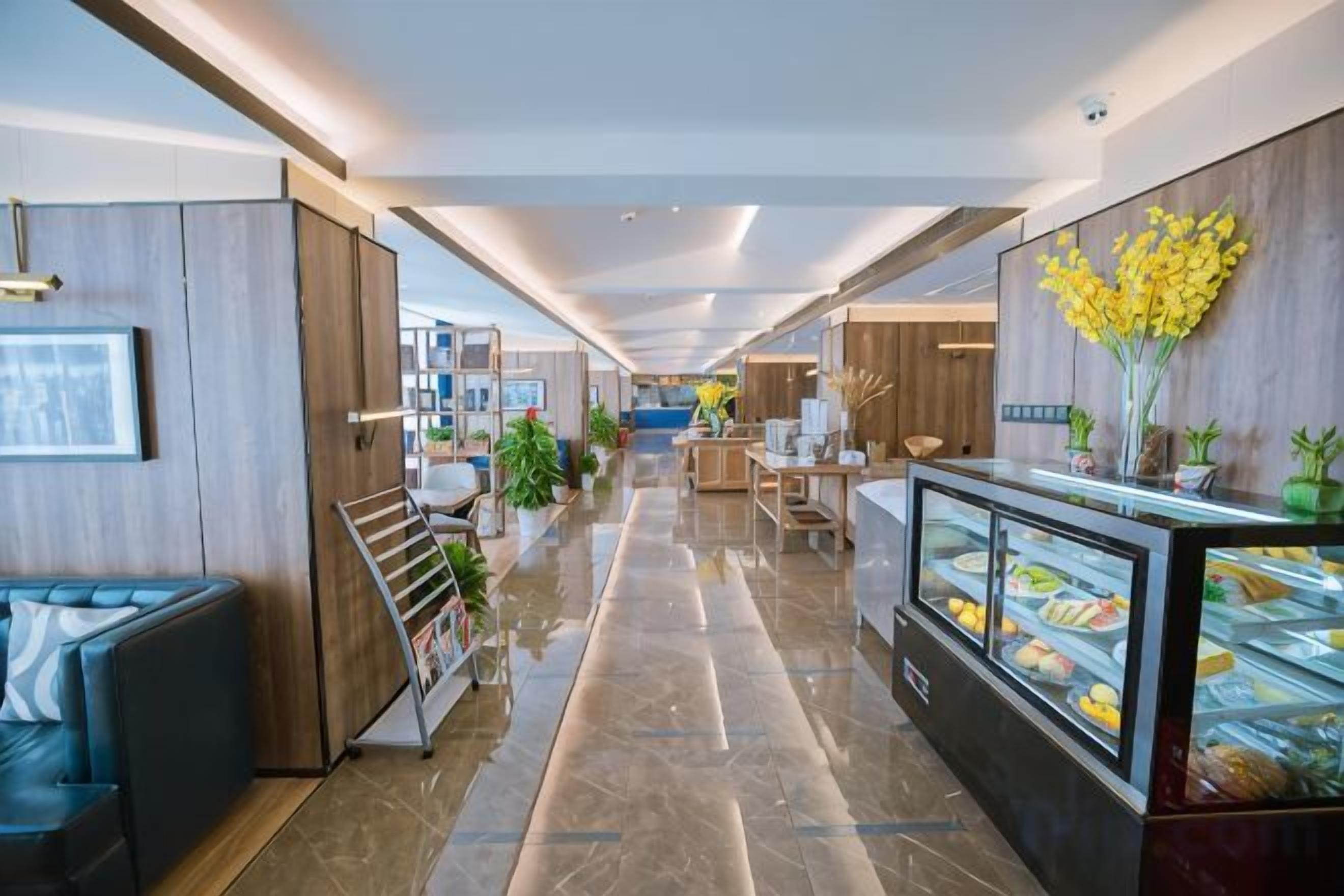 Un couloir d’hôtel comprenant un espace de réception, des sièges et une vitrine où sont exposés des produits alimentaires.