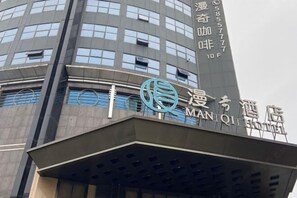 A hotel with a modern design, featuring a prominent logo and signage indicating it is the Manqi Hotel.