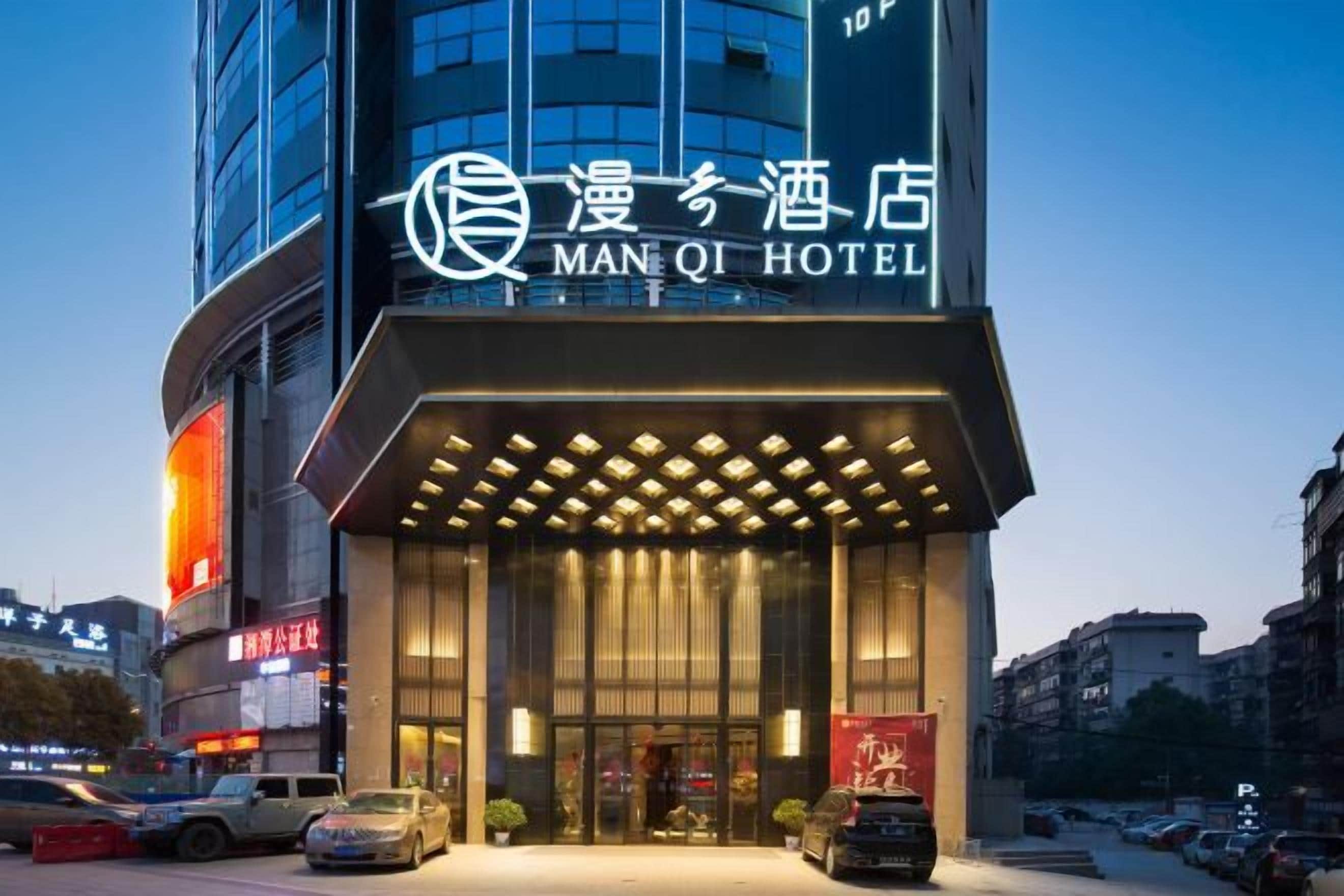 A hotel entrance with a modern design, featuring a prominent sign and a covered entrance area.