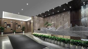 A modern reception area with a marble counter, plants, and a black carpet.