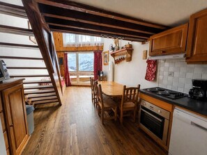 A kitchen with wooden floors, a dining table, and a stove.