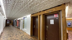 A hallway with patterned flooring, wooden doors, and a ceiling with a textured design.