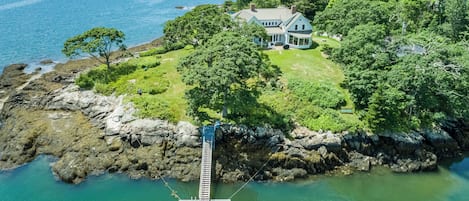 Ein Küsteneigentum mit Anlegesteg, ein Haus, umgeben von Bäumen, und Blick auf das Meer.