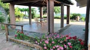 A covered outdoor seating area with brick pillars, a table, and chairs. - VILLA UVA E STELLE in the quiet of the green hills (Itri)