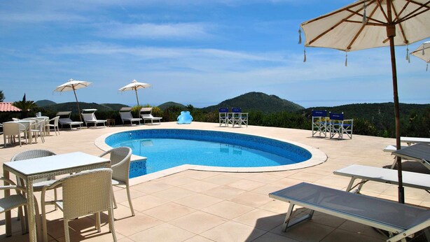 A swimming pool with lounge chairs and umbrellas, surrounded by a tiled patio. - VILLA UVA E STELLE in the quiet of the green hills (Itri)