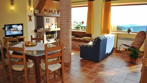 A living room with a fireplace, dining area, and a sofa. - VILLA UVA E STELLE in the quiet of the green hills (Itri)