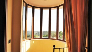 A corner room with a curved wall and a large window offering a view of greenery and hills. - VILLA UVA E STELLE in the quiet of the green hills (Itri)