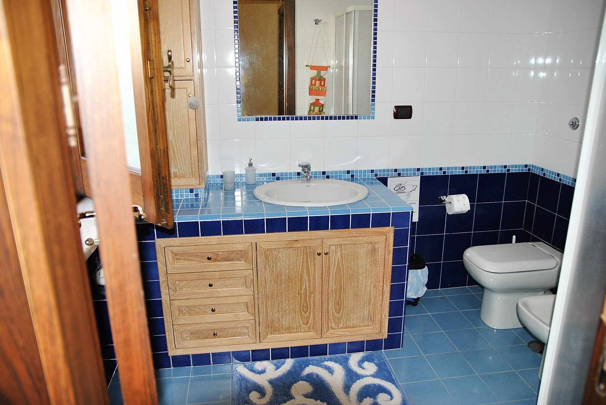 Un baño con tocador de madera, un lavamanos y un inodoro.