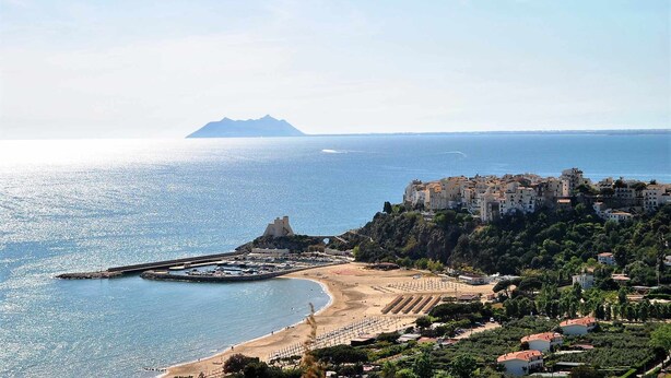 A coastal town with a beach, a pier, and buildings on a hillside. - VILLA CORBEZZOLO between nature and the sea (Sperlonga)