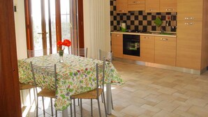 A kitchen with wooden cabinets, a built-in oven, and a dining area with a table and chairs.