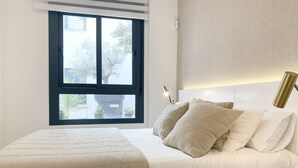 Een slaapkamer met een bed, een raam en een bedlamp.