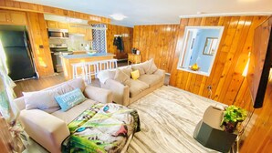 Una sala de estar acogedora con un sofá, un plaid estampado y un comedor con barra.