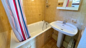Un baño con bañera, lavamanos y espejo.