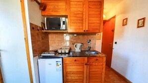Una cocina funcional con armarios de madera, microondas, refrigerador y lavamanos.