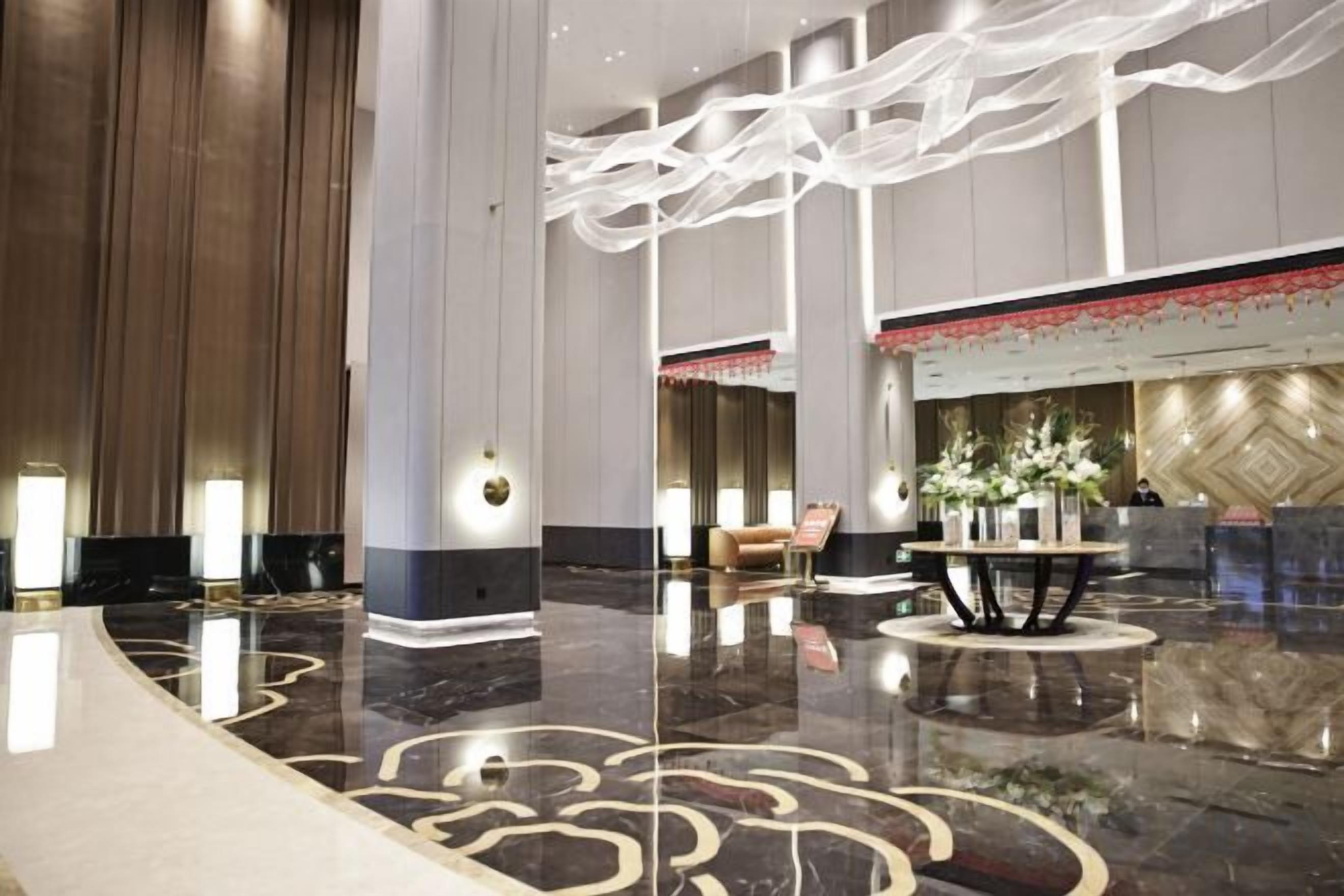 A spacious lobby with a polished marble floor, a reception desk, and a seating area.