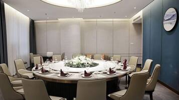 A conference room with a round table, chairs, and a chandelier.