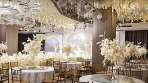 Une salle de banquet avec des tables rondes, des chaises et des centres de table floraux.