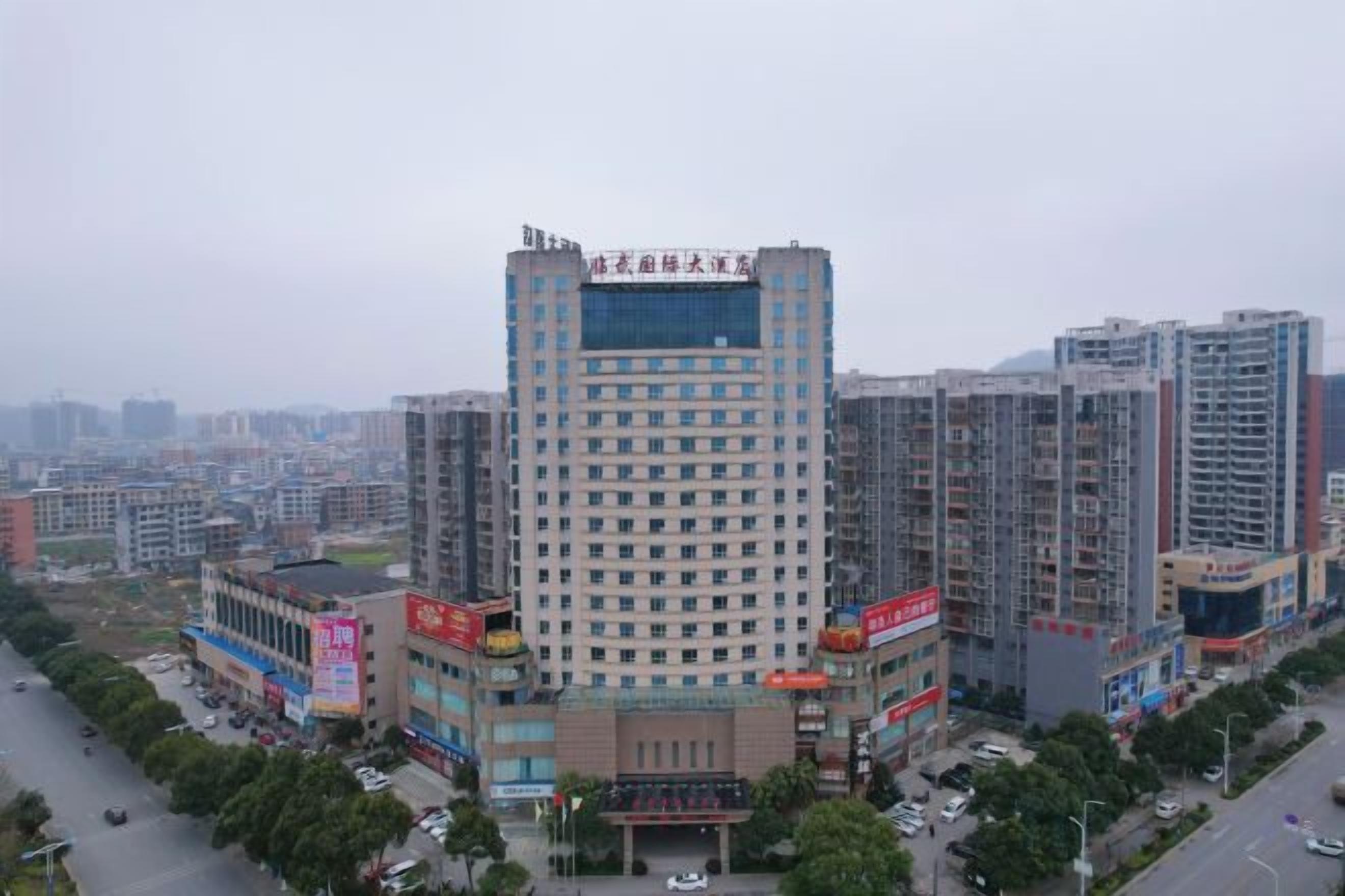 A high-rise building with multiple floors, surrounded by other buildings, and a road with vehicles.