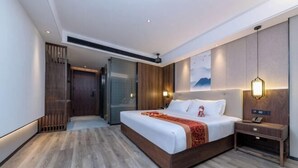 Une chambre d’hôtel moderne, dotée d’un grand lit, d’une table de chevet, d’une lampe fixée au mur et d’une porte coulissante donnant accès à la salle de bain.