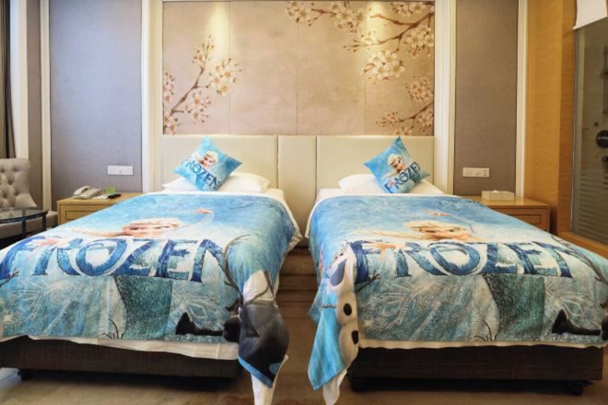 Ein Hotelzimmer mit zwei Betten, jeweils mit einer Bettdecke mit Frozen-Motiv.
