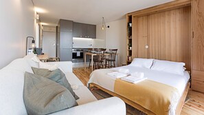 Une chambre d’hôtel moderne dotée d’un grand lit, d’un canapé, d’un coin repas et d’une cuisine.