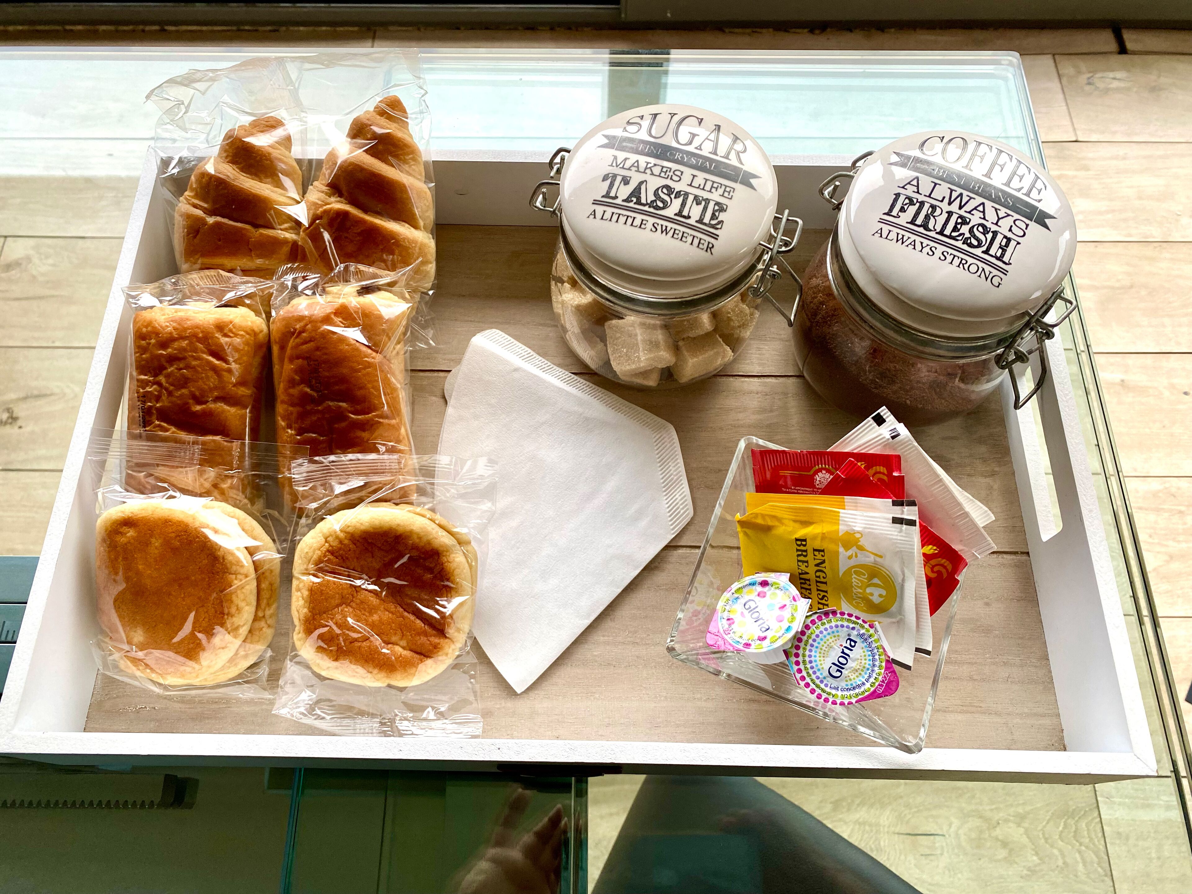 A tray with pastries, sugar and coffee jars, napkins, and Gloria brand cookies.