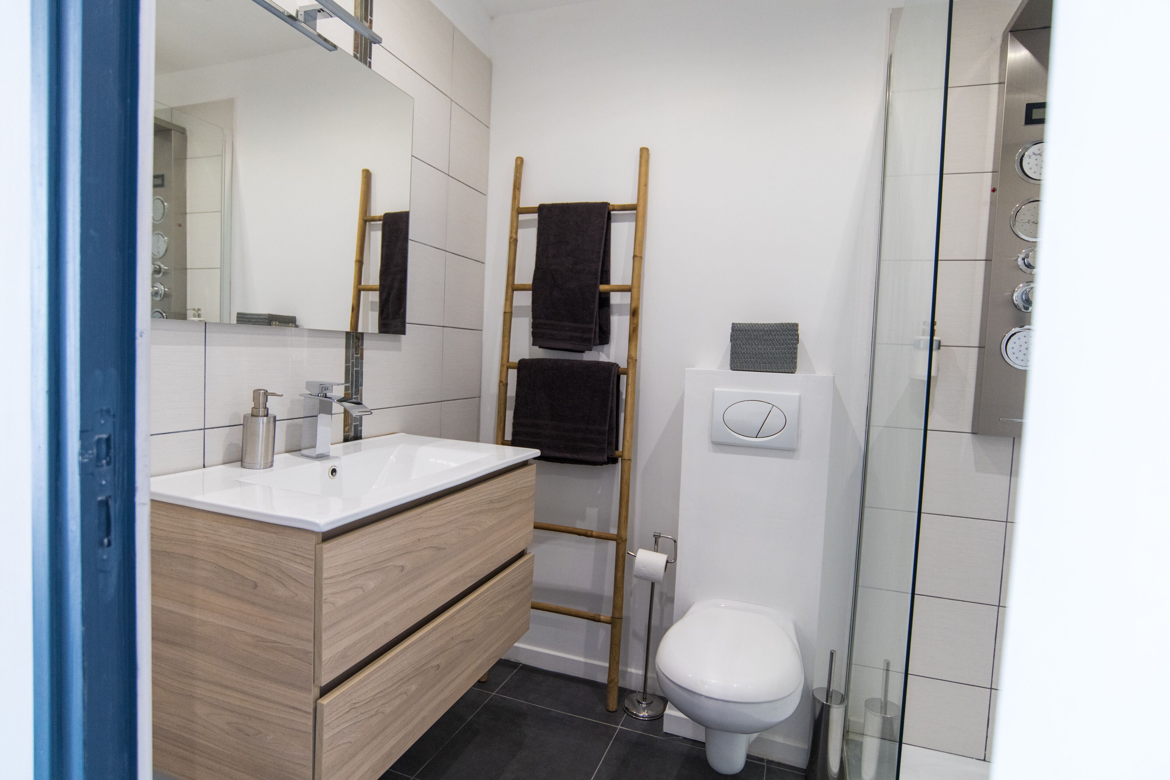 Um banheiro moderno com toucador de madeira, vaso sanitário e box de vidro.