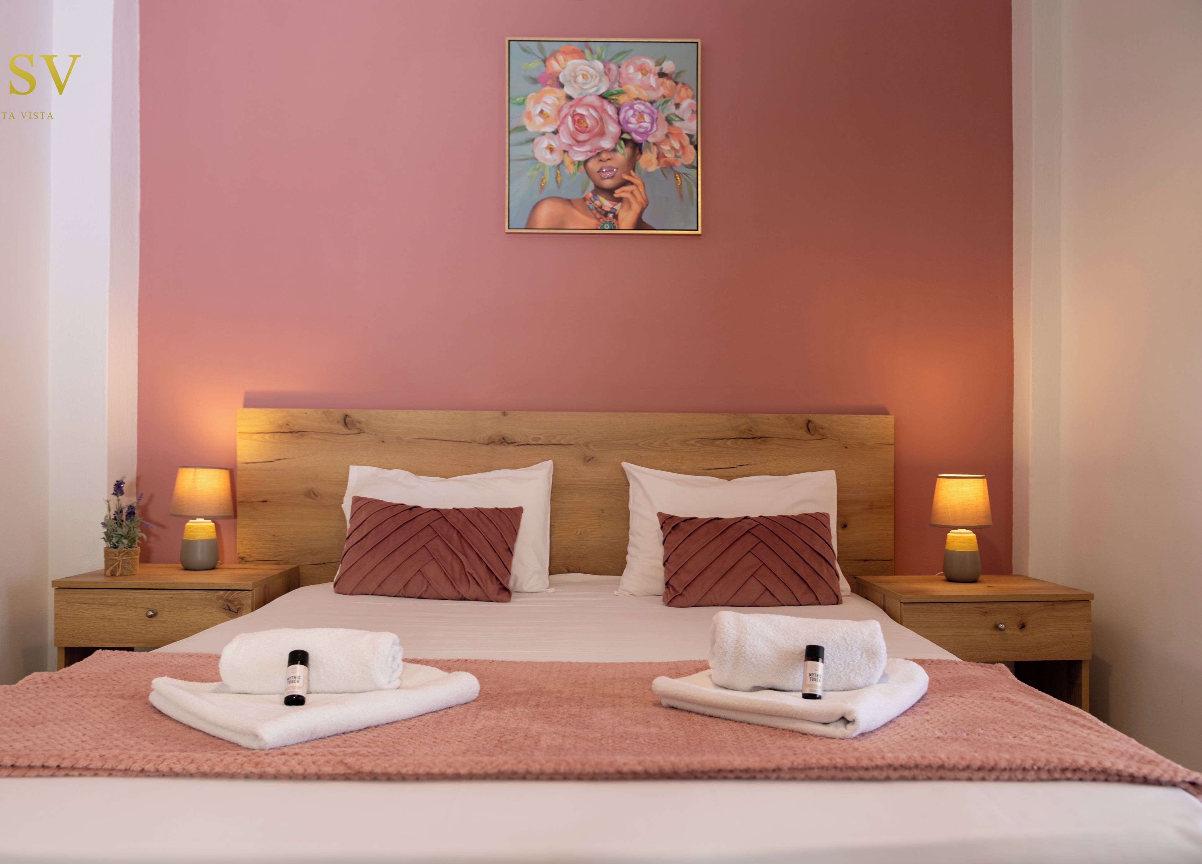 Une chambre d’hôtel avec une tête de lit en bois, deux tables de chevet avec des lampes, un tableau au mur et des serviettes sur le lit.