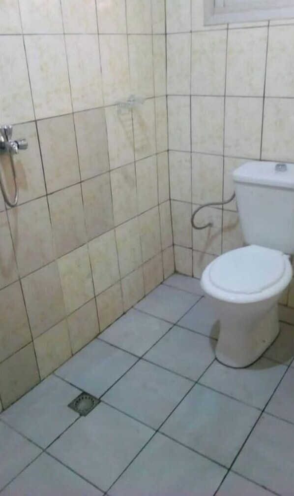 A bathroom with a toilet, a shower, and tiled walls.