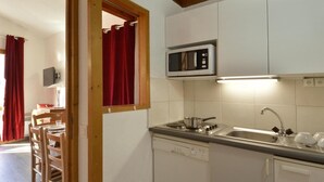 A compact kitchen with white cabinets, a microwave, a stove, and a sink. - 100m from ski slopes, 4th floor, view ski slopes, balcony, tv, ski locker, 32m², La Plagne (La Plagne)