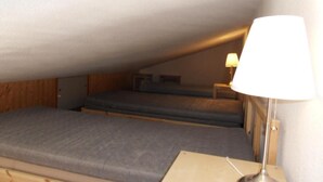A small attic bedroom with two beds, a nightstand, and a lamp. - 100m from ski slopes, 4th floor, view ski slopes, balcony, tv, ski locker, 32m², La Plagne (La Plagne)