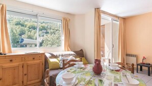 Un coin repas accueillant avec une table ronde dressée pour quatre personnes, un buffet en bois et une fenêtre agrémentée de rideaux.