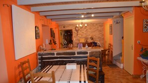 Zona de menjador amb taula preparada per a dues persones, caires de fusta, un candelabrum i una paret de pedra.