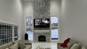 A modern living room with a fireplace, two sofas, a coffee table, and a TV mounted on the wall. - Elegant & Private Sparta Home – Pool, Deck, and Luxury Comfort (Sparta)