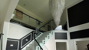 A modern interior with a staircase, a chandelier, and a bed in a bedroom. - Elegant & Private Sparta Home – Pool, Deck, and Luxury Comfort (Sparta)