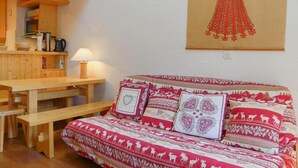Ein gemütliches Zimmer mit einer Holzbank, einem Tisch und einem Bett mit gemusterten Textilien.