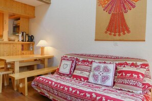 Una habitación acogedora con un banco de madera, una mesa y una cama con ropa de cama estampada.