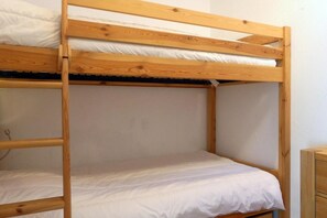 A bunk bed with a wooden frame and white bedding.