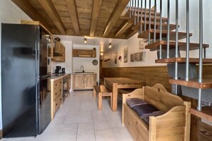 A compact kitchen with a modern refrigerator, wooden cabinets, and a dining area with a bench and table. - 10m from ski slopes, 4th floor, balcony, 55m², Méribel-Mottaret (Méribel - Les Allues)