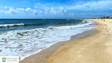 Una playa con olas, cielo despejado y el logotipo de Destination Vacation.