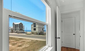 Ein Zimmer mit großem Fenster und Blick auf eine Küstenstraße sowie Gebäude.