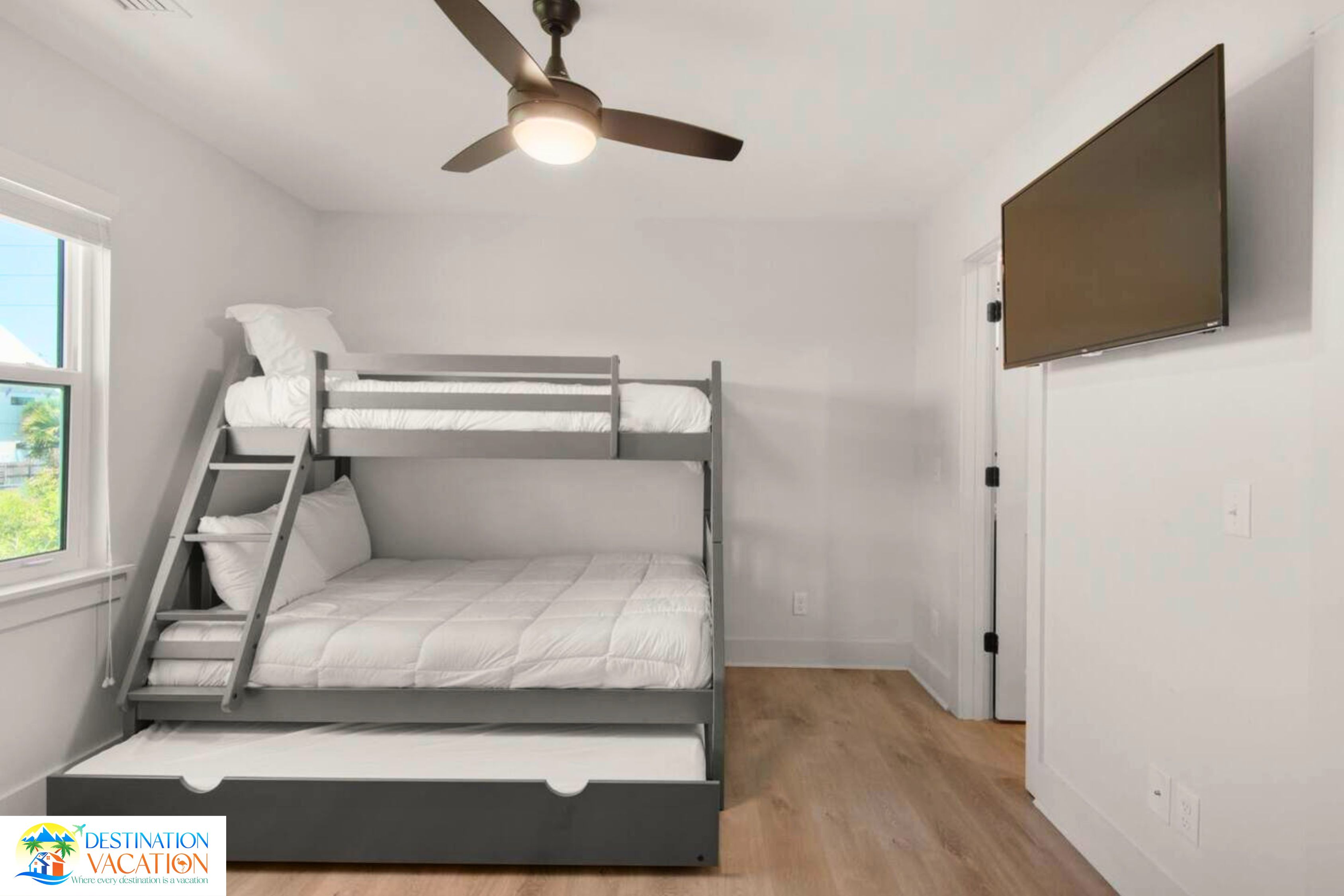A bunk bed room with a ceiling fan, a window, and a door.