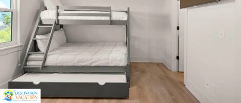 A bunk bed room with a ceiling fan, a window, and a door.