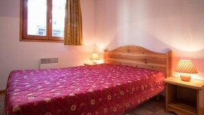 A bedroom with a wooden bed, a window with curtains, and two bedside lamps.