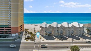Ein Hotel direkt am Strand mit mehrstöckigen Gebäuden, einem Parkplatz und freiem Blick auf das Meer.