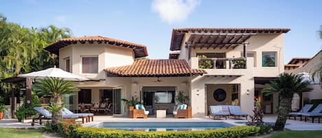 A two-story house with a swimming pool, outdoor seating, and a covered patio.