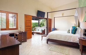 A bedroom with a four-poster bed, a desk, and a chair.